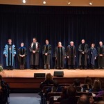 Faculty members stand on stage waiting for their award